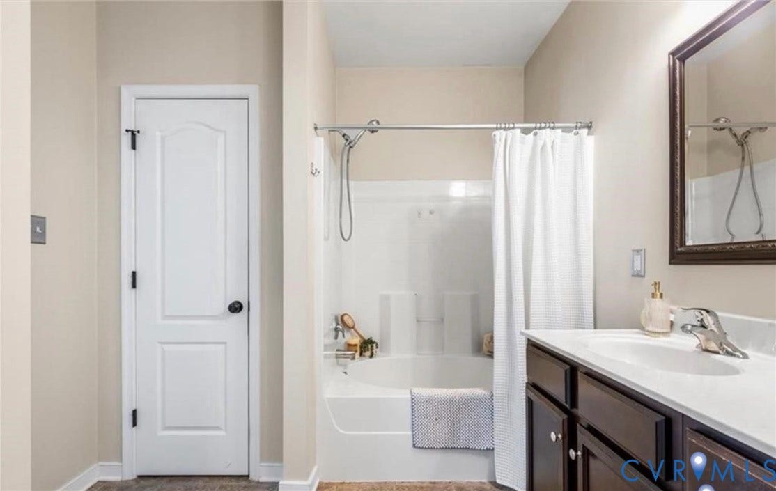7319 Vicenzo Drive, Moseley, VA 23120 White bathtub with an integrated shower, dark wood-finish vanity with a white countertop, and wood-finish flooring