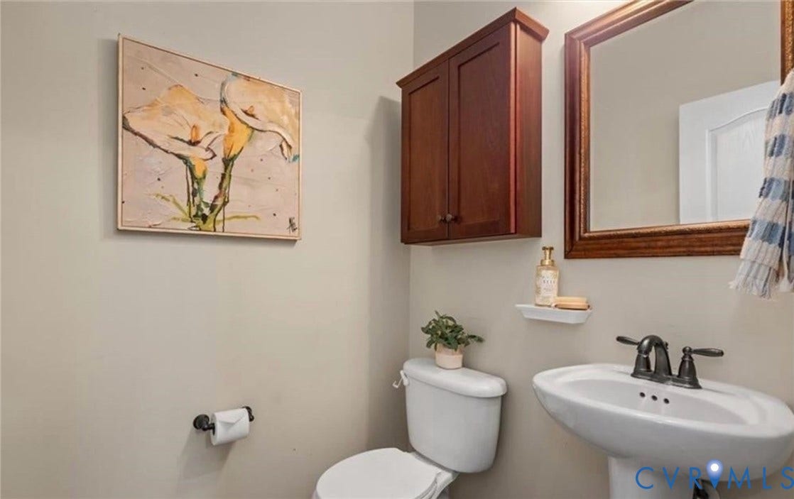 7319 Vicenzo Drive, Moseley, VA 23120 Pedestal sink with dark bronze faucet, framed mirror, wall-mounted wood-finish cabinet, and a white toilet
