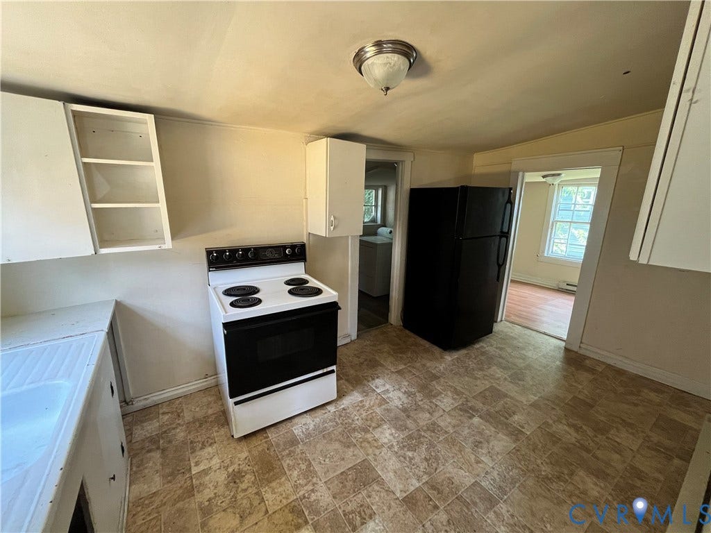 927 Farmer Street, Petersburg, VA 23803 Kitchen featuring white cabinetry, a freestanding range, a black refrigerator, and patterned floor tiling