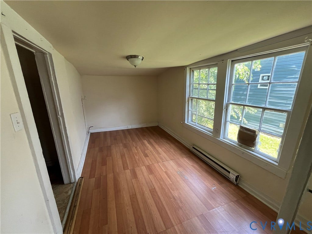 927 Farmer Street, Petersburg, VA 23803 Wood-finish flooring, two large windows, white trim, wall-mounted heating unit, and a ceiling-mounted light fixture