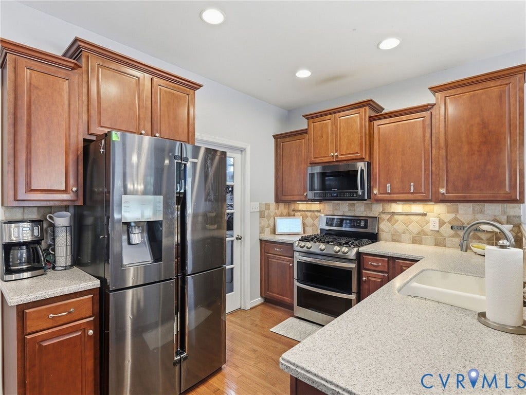 13925 Gorham Lane, Charter Colony, Midlothian, VA 23114 Kitchen featuring stainless steel appliances, wood-finish cabinetry, speckled countertops, and a tiled backsplash