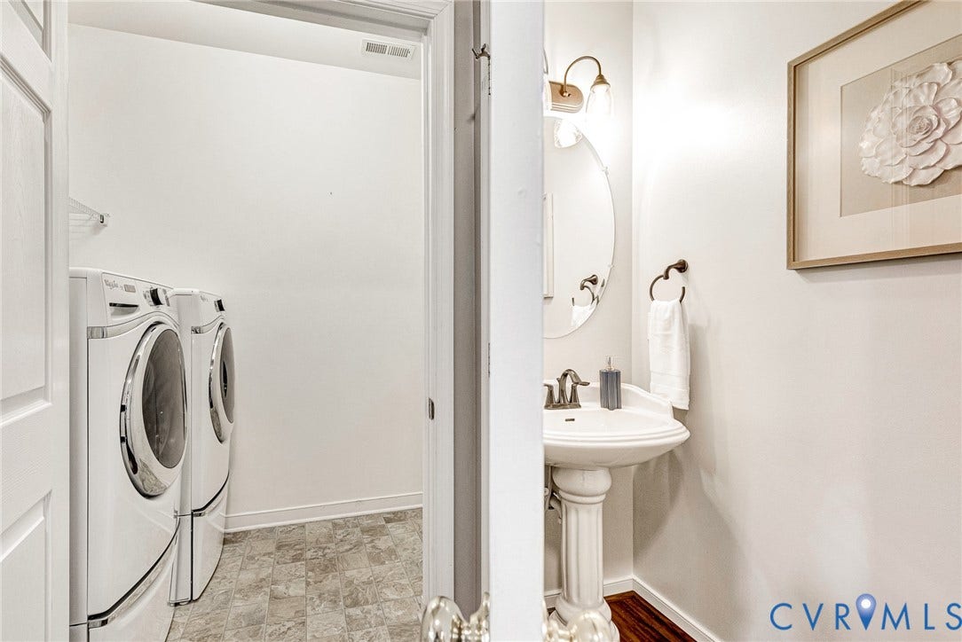 7728 Marshall Arch Drive, Liberty Trace, Mechanicsville, VA 23111 Pedestal sink with an oval mirror, wall-mounted light fixture, and dark wood-finish flooring