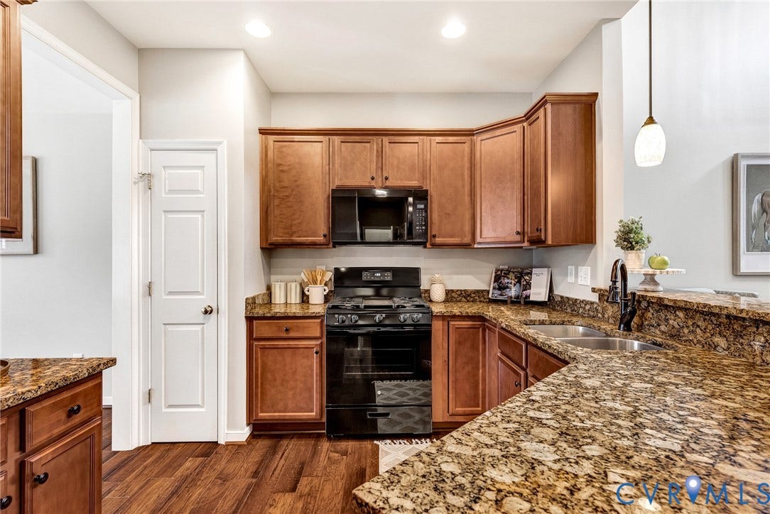 7728 Marshall Arch Drive, Liberty Trace, Mechanicsville, VA 23111 Kitchen featuring wood-finish flooring, rich wood cabinetry, stone countertops, a stainless steel double sink, and black appliances