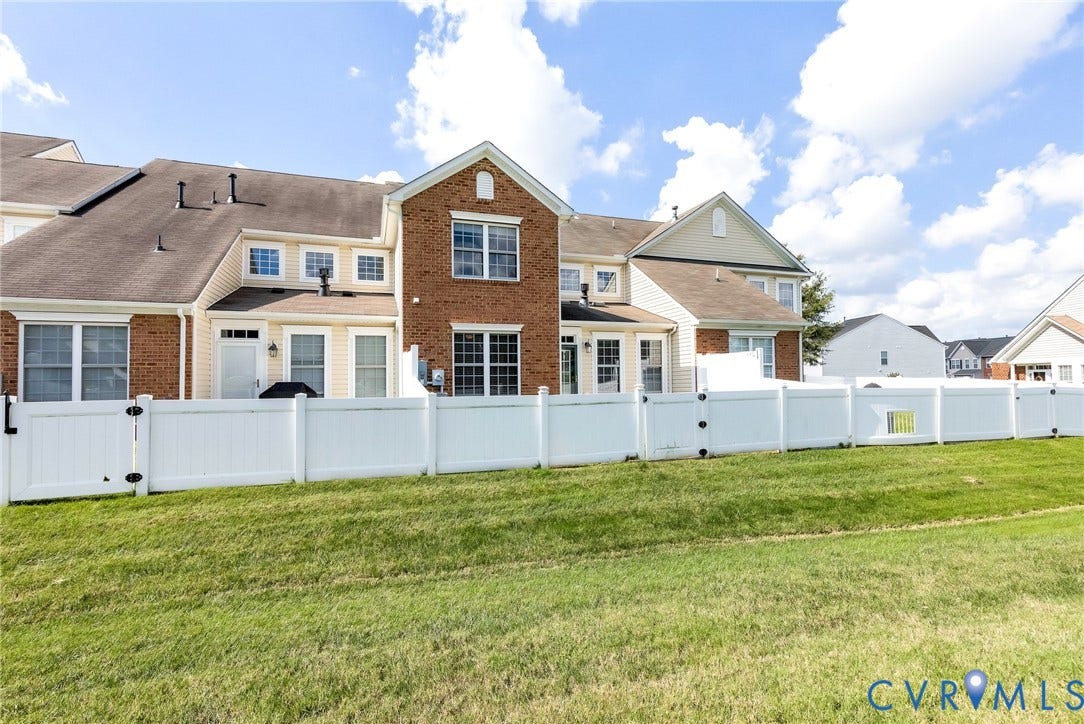 7728 Marshall Arch Drive, Liberty Trace, Mechanicsville, VA 23111 Rear exterior featuring brick and siding finishes, multiple windows, a white privacy fence, and a green lawn
