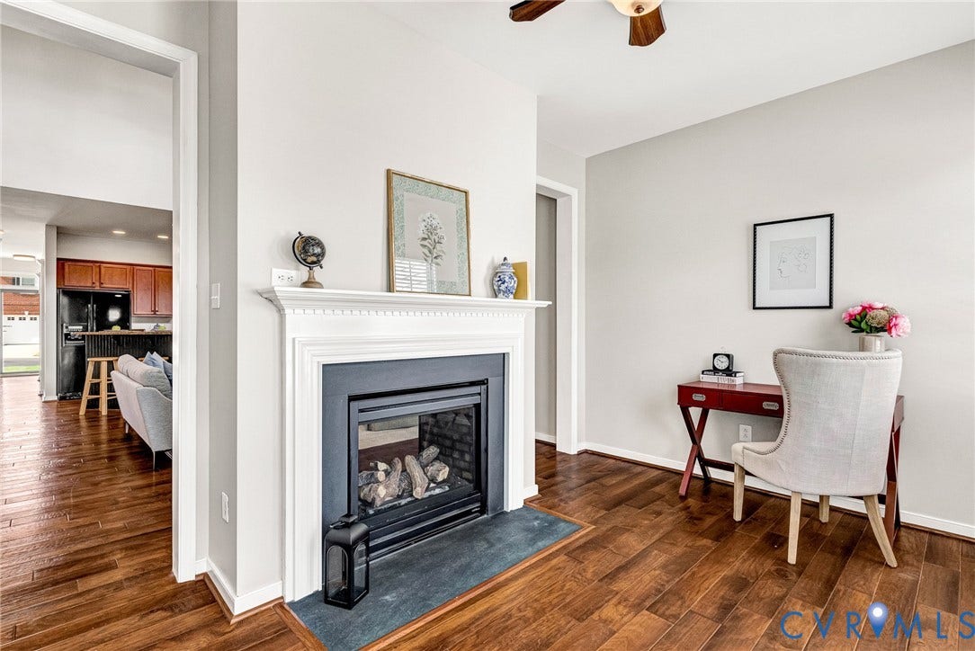 7728 Marshall Arch Drive, Liberty Trace, Mechanicsville, VA 23111 Wood-finish flooring throughout, a gas fireplace with a classic white mantel, and a ceiling fan with integrated lighting
