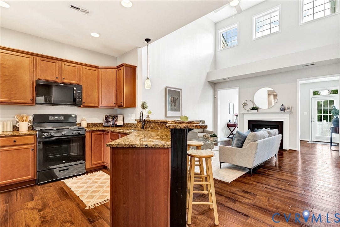 7728 Marshall Arch Drive, Liberty Trace, Mechanicsville, VA 23111 Open-concept kitchen featuring wood-finish cabinetry, black appliances, and granite countertops with a breakfast bar
