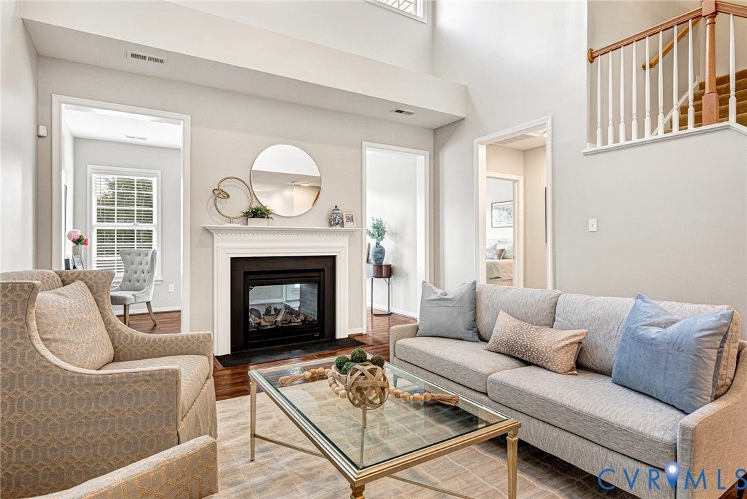 7728 Marshall Arch Drive, Liberty Trace, Mechanicsville, VA 23111 Living area featuring a white mantel fireplace with a black insert, high ceilings, wood-finish flooring, and a staircase with wood handrails and white balusters