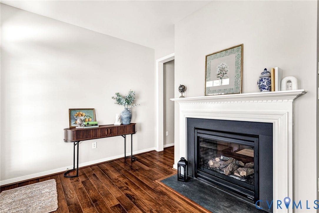 7728 Marshall Arch Drive, Liberty Trace, Mechanicsville, VA 23111 Hardwood flooring, white painted walls, white mantel, and a black fireplace insert with a stone hearth