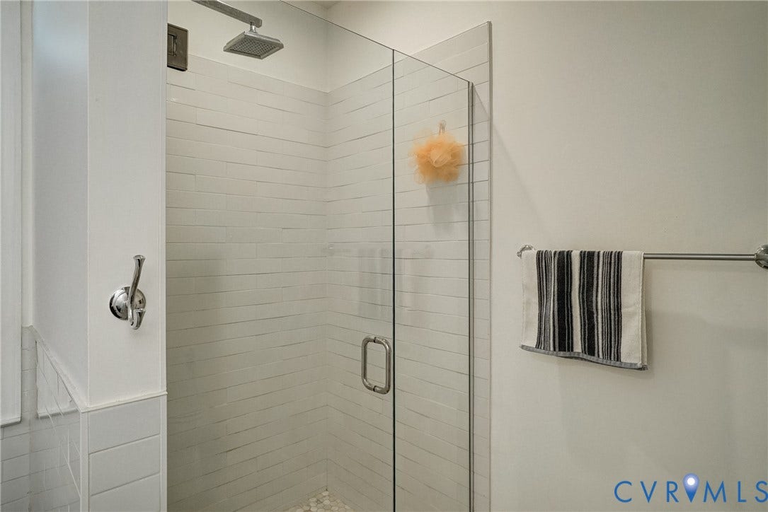 8805 Eli Place, Kings Forest, Glen Allen, VA 23060 Glass-enclosed shower featuring a rain showerhead, white horizontal tile, and a pebble-finish floor