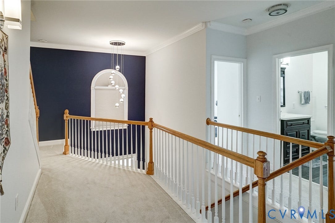 8805 Eli Place, Kings Forest, Glen Allen, VA 23060 Carpeted hallway featuring a wood and white spindle railing, decorative arched wall niche, and contemporary pendant lighting