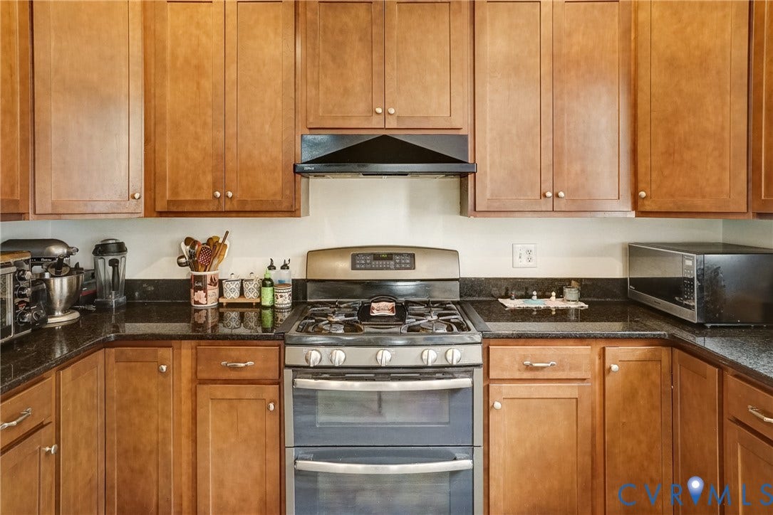 8805 Eli Place, Kings Forest, Glen Allen, VA 23060 Wood-finish cabinetry, dark countertops, and stainless steel range with overhead ventilation