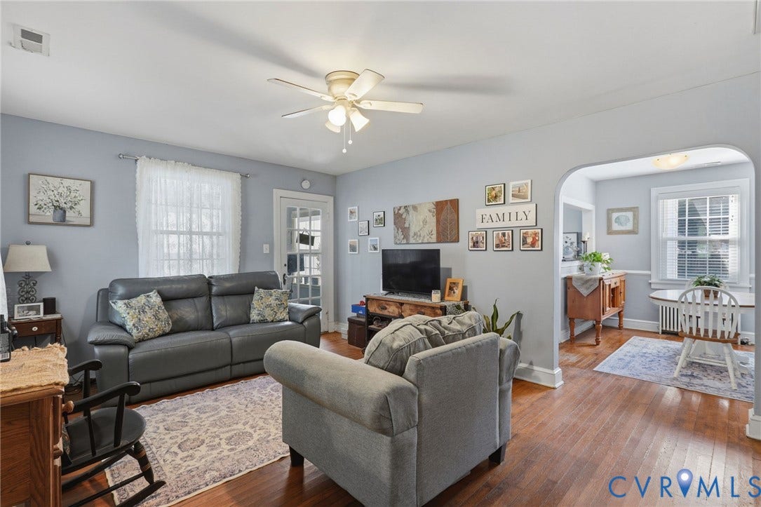 Hardwood-finish flooring, light blue wall paint, ceiling fan with integrated lighting, glass-paned exterior door, and an arched doorway