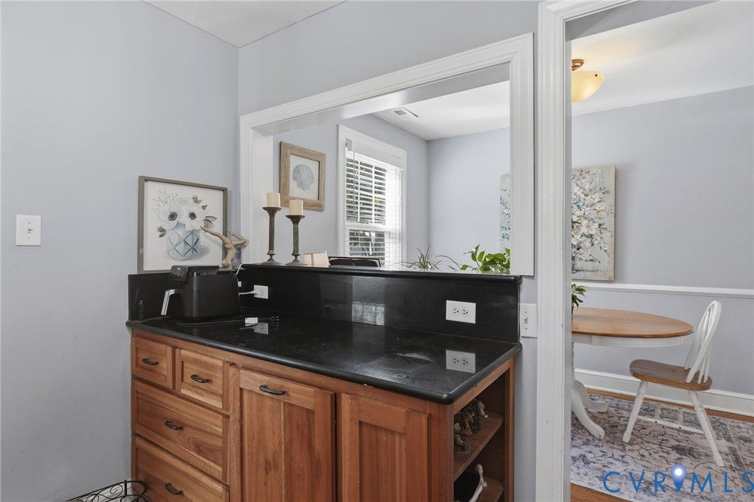 Wood-finish cabinetry with dark hardware, dark countertop, and a pass-through window