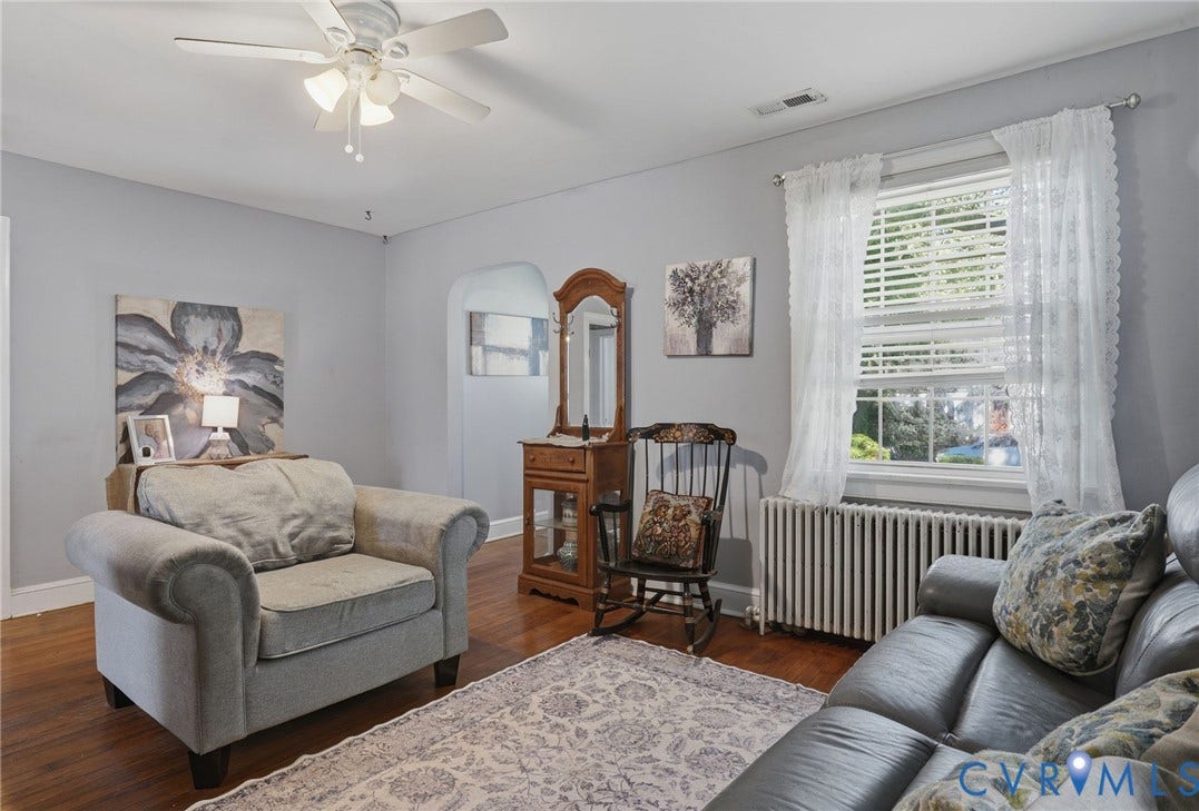 Wood-finish flooring with a ceiling fan, arched doorway, and windows with blinds
