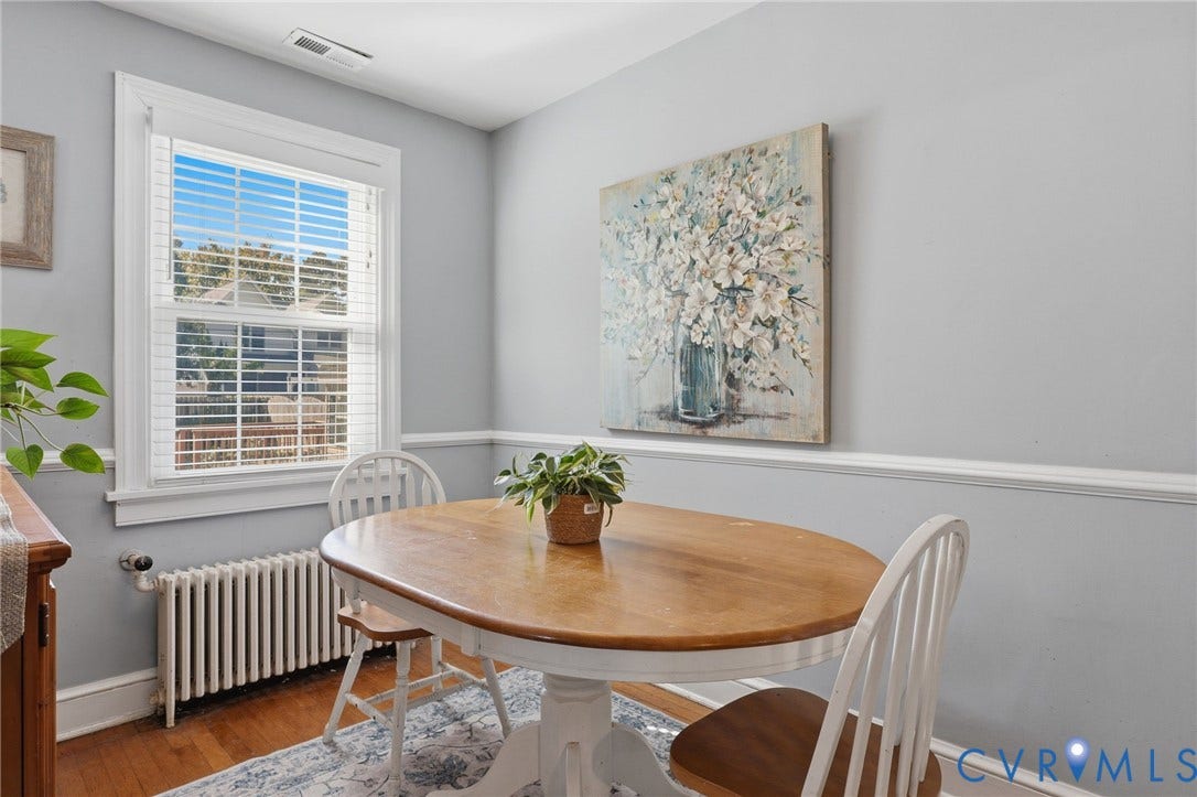 Hardwood flooring, painted walls with chair rail molding, and a window with blinds