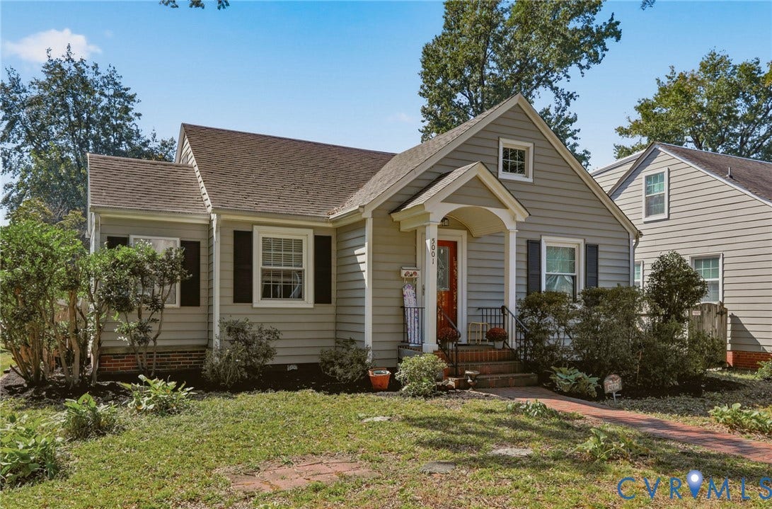 Light gray siding exterior with a red-orange front door, covered entry, and black window shutters
