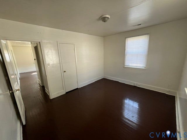 1227 Montgomery Avenue, Birdville Park, Petersburg, VA 23803 Wood-finish flooring, white painted walls, single window with blinds, overhead light fixture, and a solid white door