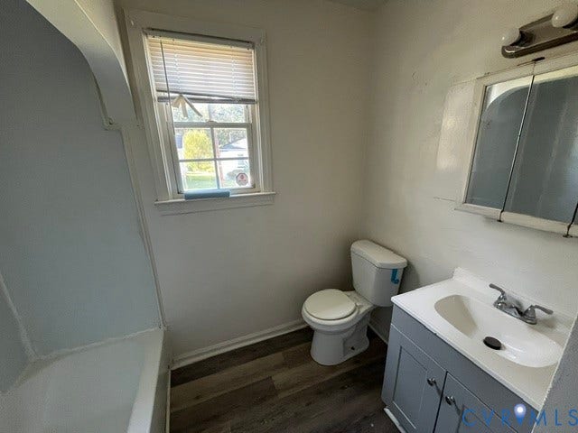 1227 Montgomery Avenue, Birdville Park, Petersburg, VA 23803 Tub and shower combination, gray vanity with integrated sink, wood-finish flooring, and a window
