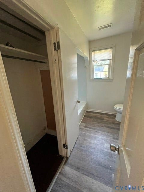 1227 Montgomery Avenue, Birdville Park, Petersburg, VA 23803 Bathroom featuring a built-in bathtub, toilet, and a window with blinds