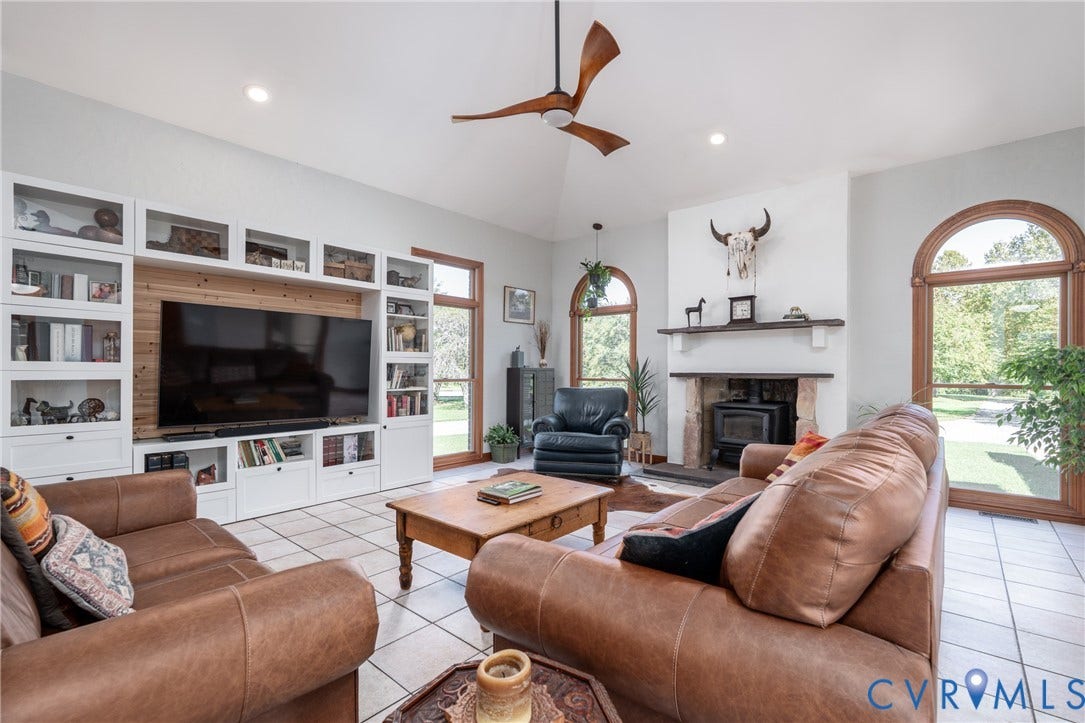 The living room features a fireplace and distinctive arched windows overlooking the property.