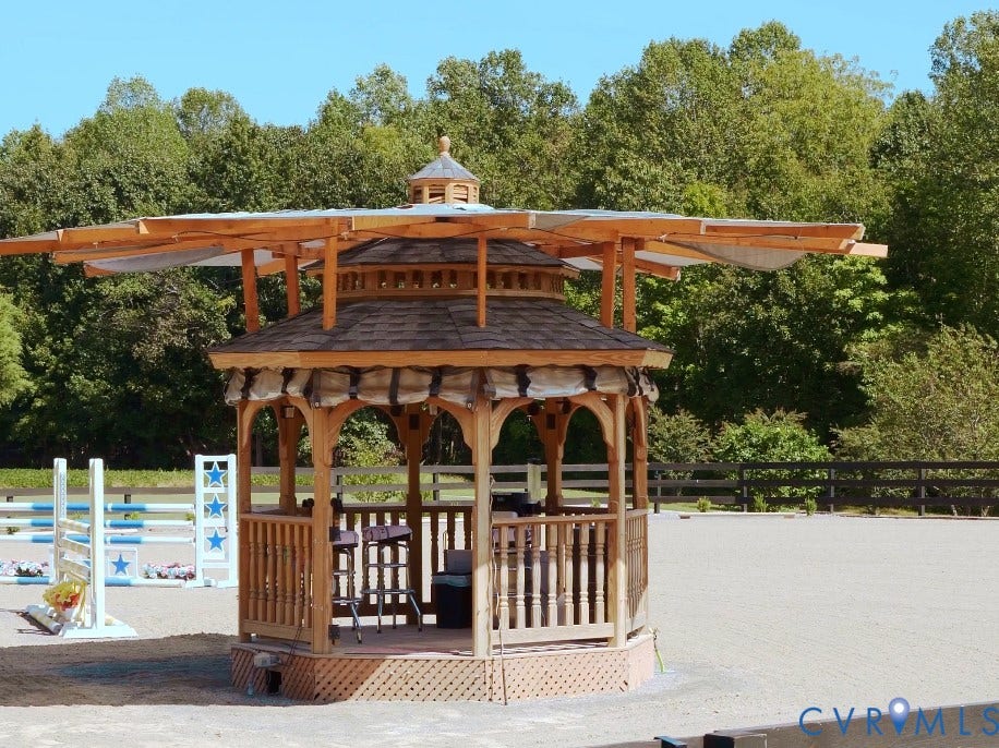 Trainer's gazebo in the main ring with misting system, fans, heater, roll-down enclosed sides, and shade.