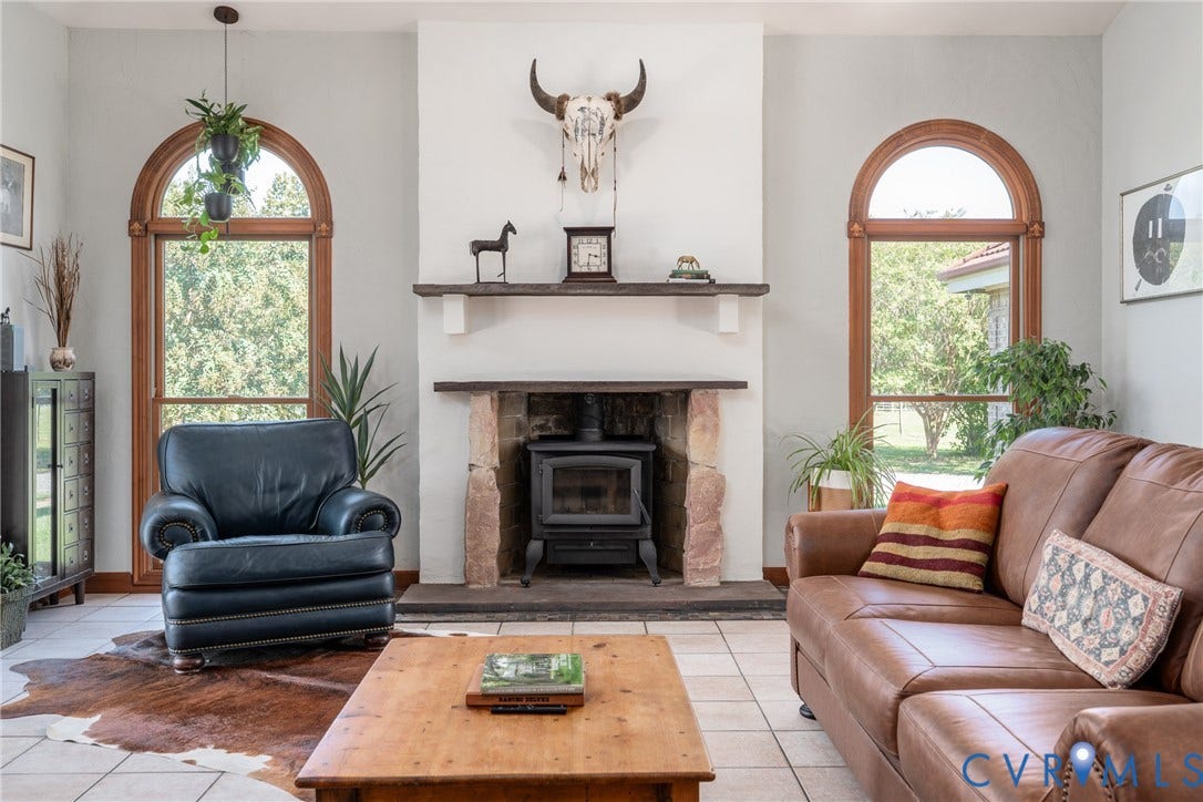 Arched wood-framed windows flank a stone fireplace with a wood-burning stove
