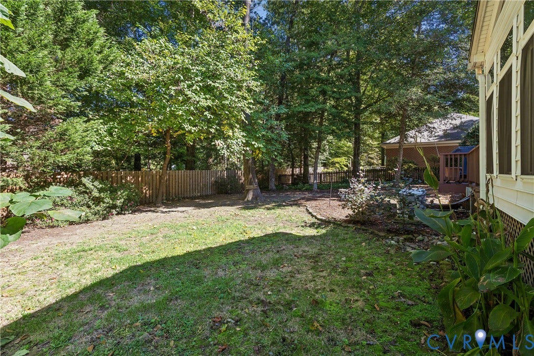 Expansive backyard with a manicured lawn, established landscaping, privacy fencing, and a screened-in porch with vinyl siding