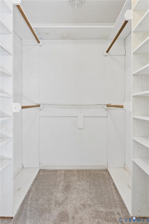 Built-in shelving, multiple hanging rods, and carpet flooring