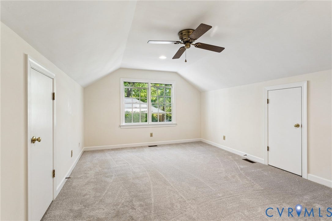 Room with vaulted ceiling, central window, ceiling fan, and light gray carpeting