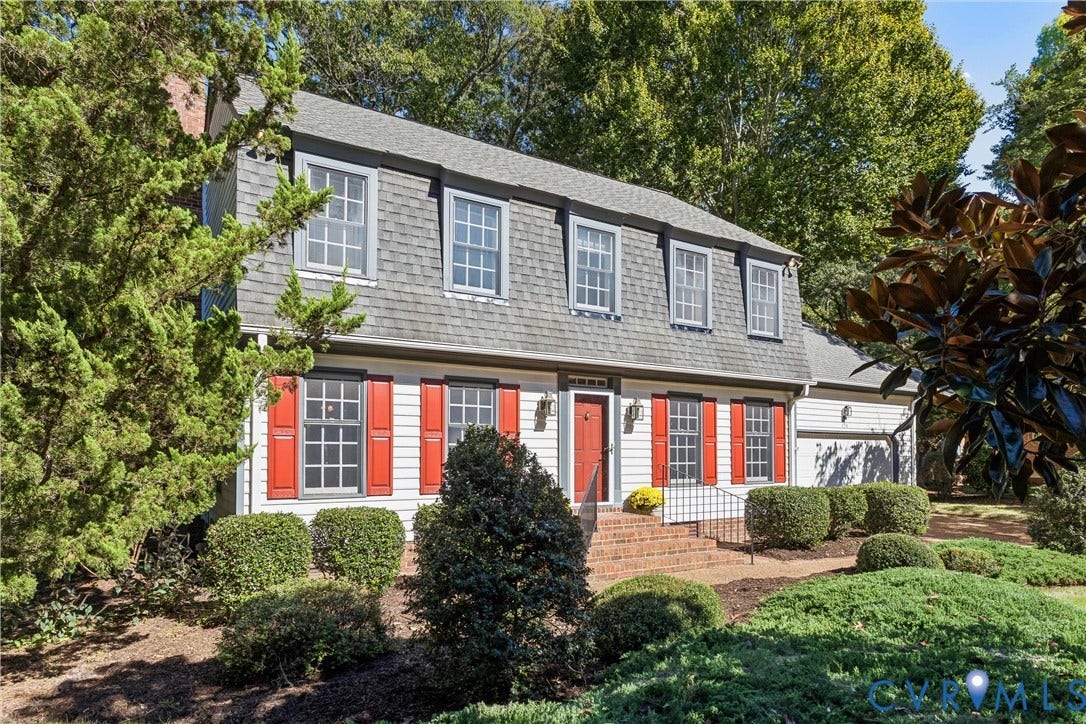 White siding exterior with a mansard roof, dormer windows, and red shutters