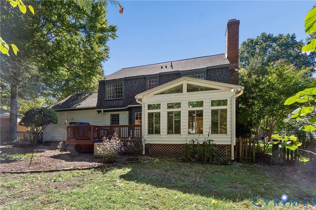 Expansive backyard featuring a multi-level deck, sunroom with large windows, and mature trees
