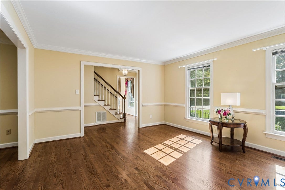 Wood-finish flooring throughout, bright walls, crown molding, and wainscoting