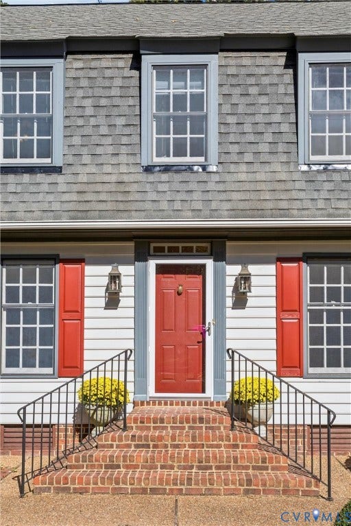 Brick front steps with black metal railings, leading to a red panel door with integrated transom lighting