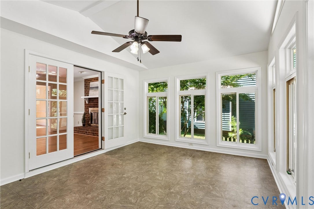 Vaulted ceiling with a ceiling fan, French doors, multiple large windows, and patterned flooring