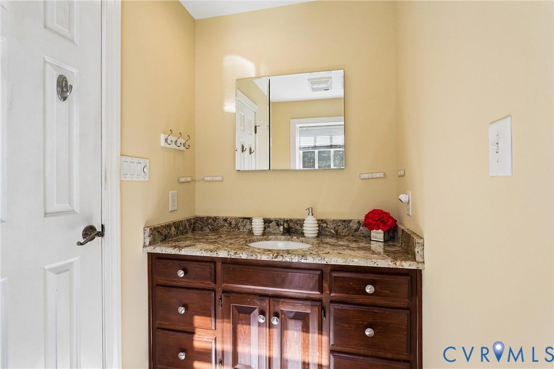 Vanity with a surface-mounted sink, wood-finish cabinetry, and a stone countertop
