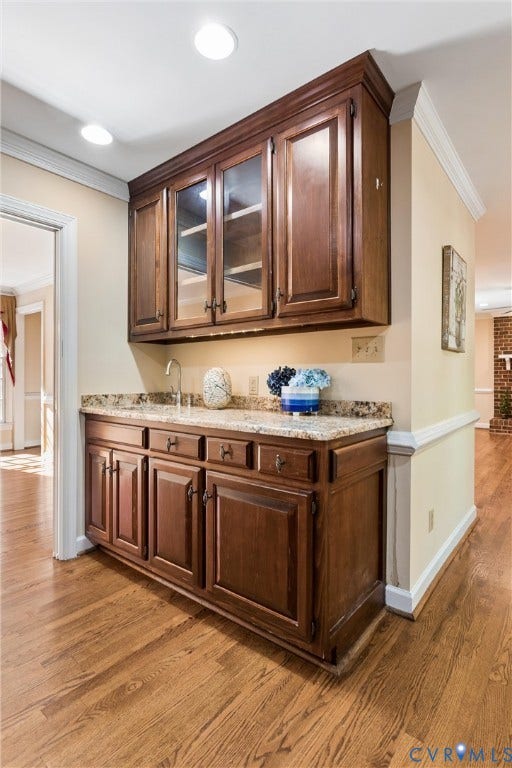 Built-in cabinetry with glass-front uppers, light-toned countertop, and undermount sink