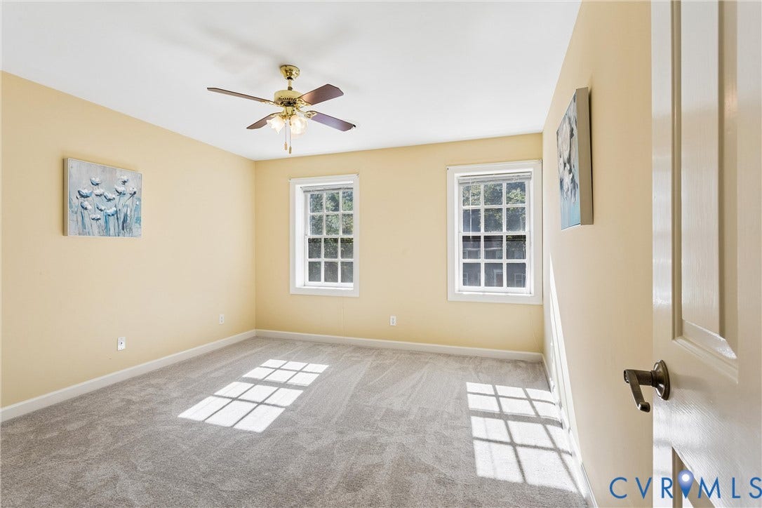 Neutral tone wall paint, two double-hung windows, and a ceiling fan with light fixture