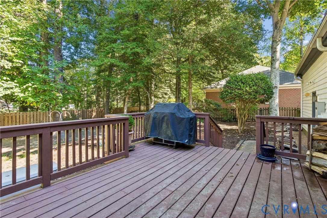 Expansive composite deck featuring horizontal wood-finish decking, substantial dark-stained railings with geometric balusters, and built-in seating areas