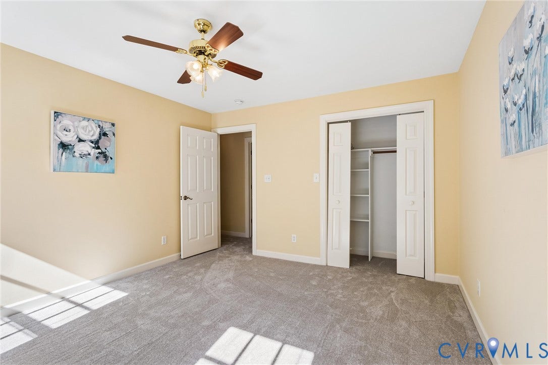 Wall-to-wall carpeting, ceiling fan with light fixture, and closet with built-in shelving