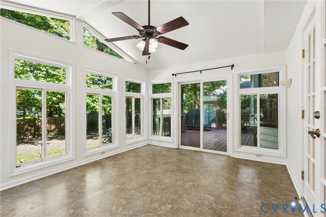 Vaulted ceiling, ceiling fan, expansive windows, glass sliding door, and a white French door