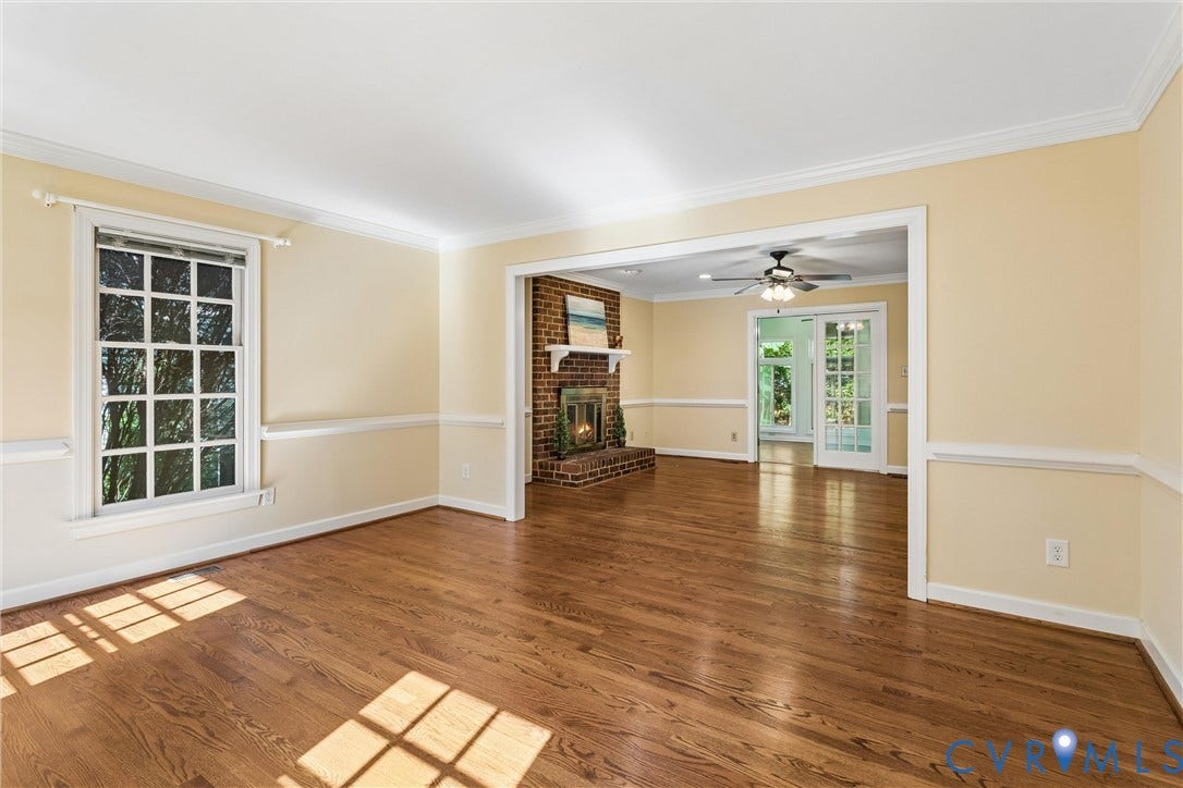 Hardwood flooring, brick fireplace with white mantel, white crown molding, white chair rail molding, and a ceiling fan