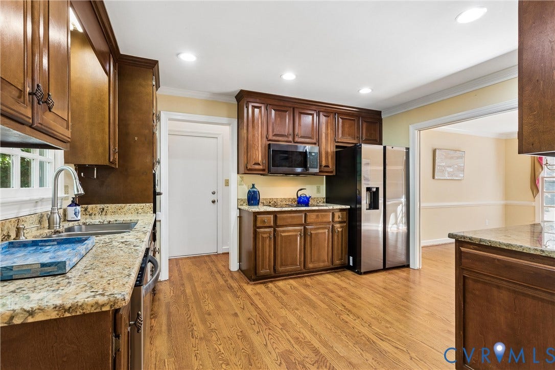 Wood-finish flooring with recessed lighting, stone countertops, and stainless steel appliances
