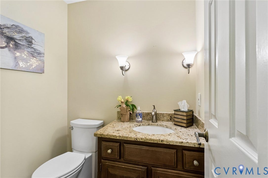 Vanity featuring a built-in sink, granite countertop, and dark wood cabinetry