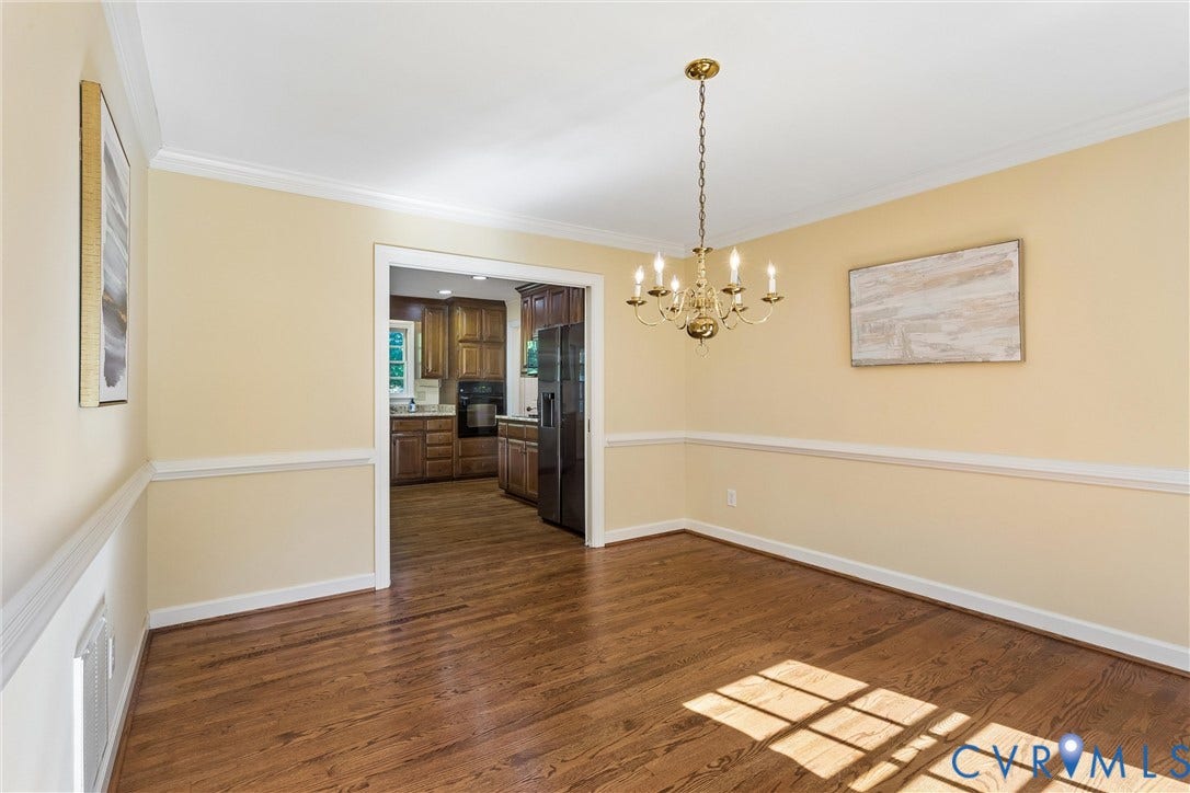 Hardwood flooring, crown molding, chair rail molding, and a brass-finish chandelier