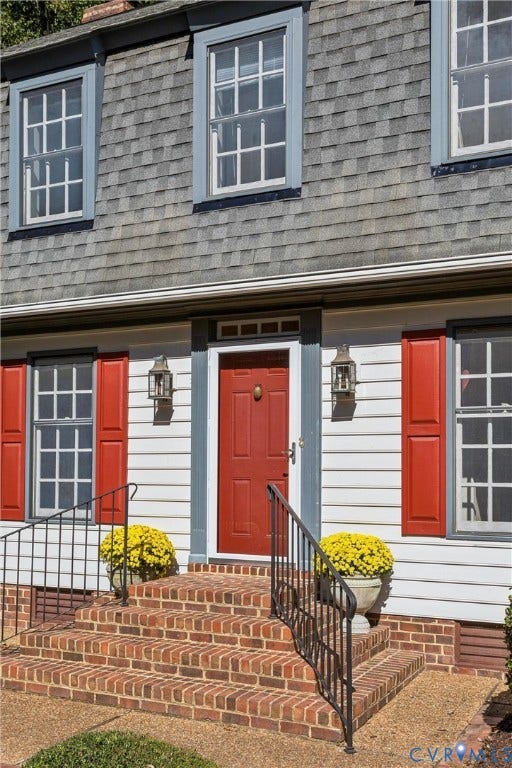 White horizontal siding with red window shutters and a red entry door