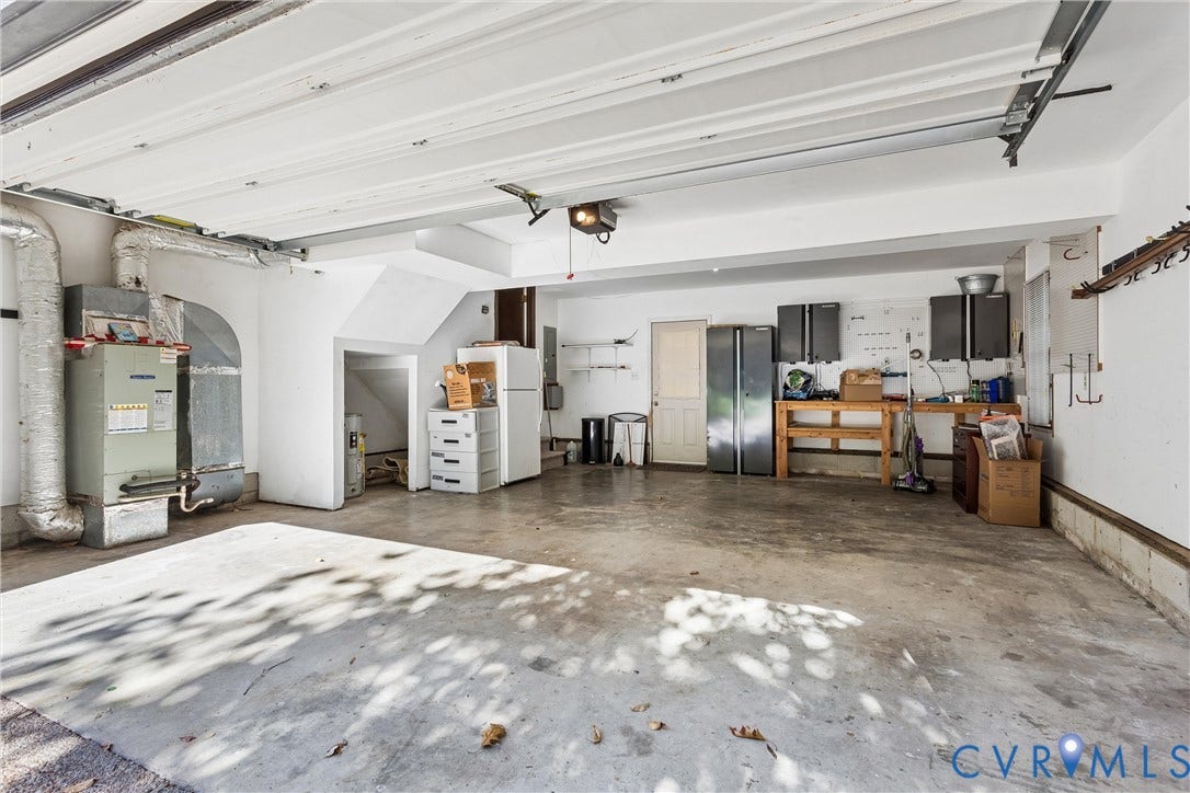 Expansive garage with concrete flooring, exposed ceiling joists, and a built-in workbench