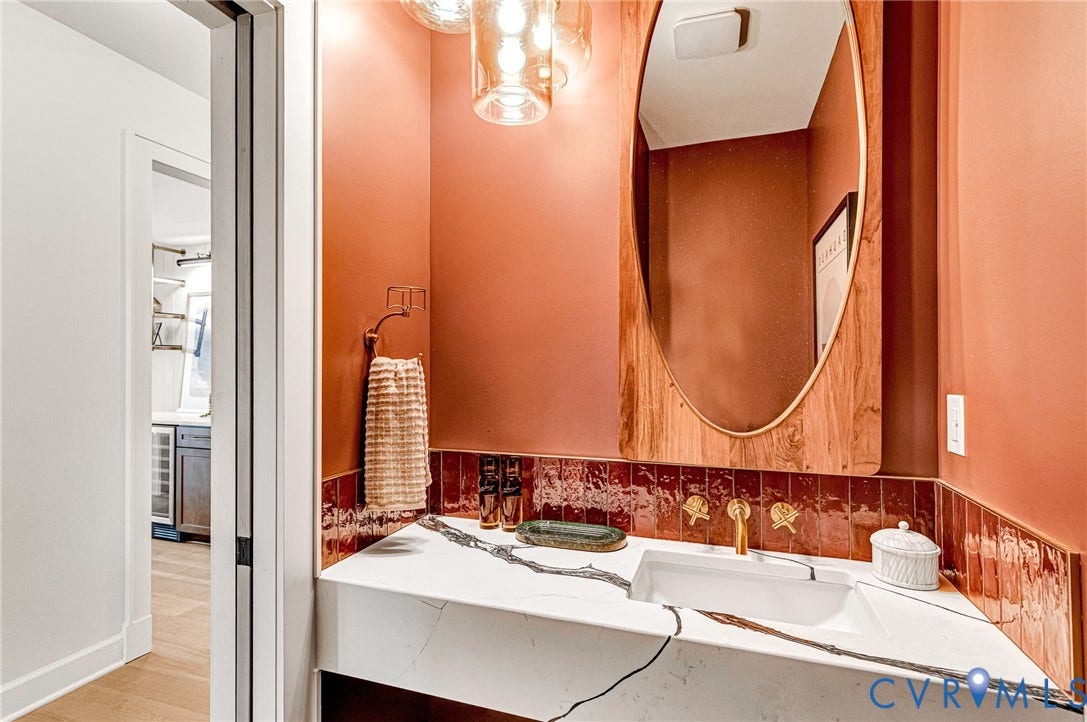 404 Waveny Road, Westham, Henrico, VA 23229 Floating vanity with a white composite countertop, rectangular basin, gold-toned faucet, warm-toned ceramic tile backsplash, and wood-framed oval mirror