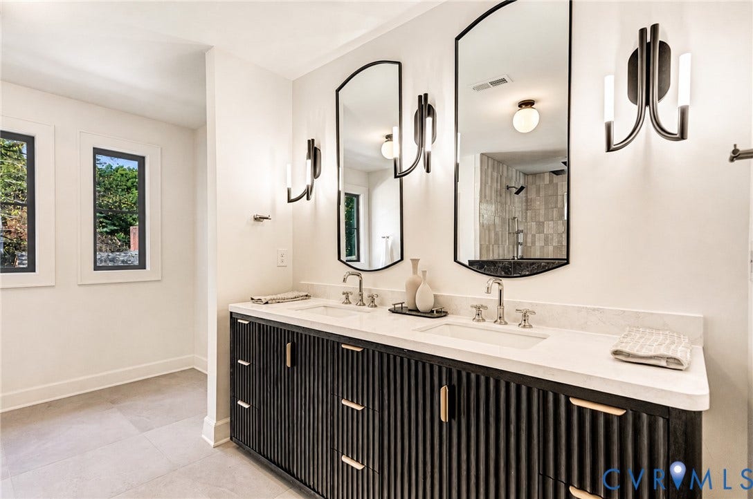 404 Waveny Road, Westham, Henrico, VA 23229 Dual-sink vanity featuring a fluted dark wood-finish cabinet, stone countertop, arched wall-mounted mirrors, and contemporary multi-arm light fixtures
