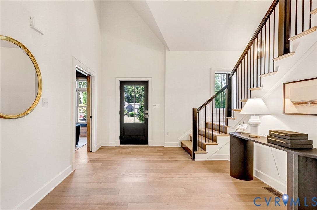 404 Waveny Road, Westham, Henrico, VA 23229 Foyer featuring vaulted ceilings, wood-finish flooring, a black paneled front door, and a staircase with stained wood treads and a black metal balustrade