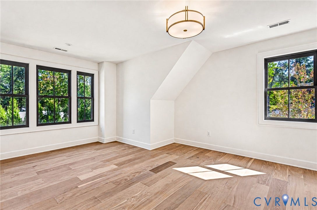 404 Waveny Road, Westham, Henrico, VA 23229 Neutral-toned room featuring wide-plank wood-finish flooring, multi-pane windows with black frames, and a modern drum-style light fixture with gold-tone metal accents